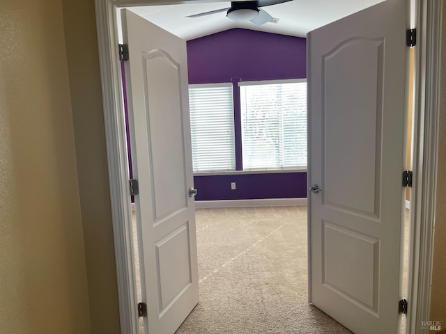 hallway with vaulted ceiling and light colored carpet