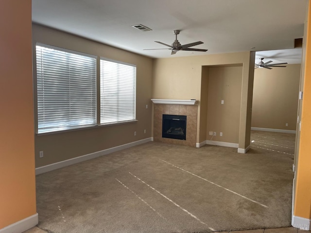 unfurnished living room with carpet floors, a tile fireplace, and ceiling fan