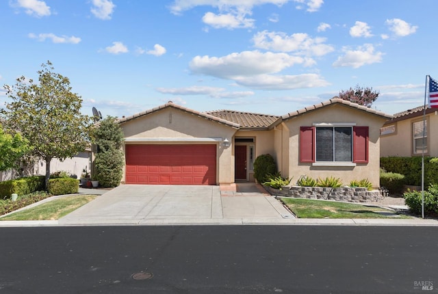 view of front of property with concrete driveway, an attached garage, a tile roof, and stucco siding