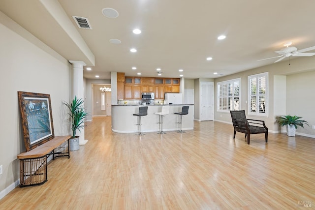 living room featuring light hardwood / wood-style flooring, decorative columns, and ceiling fan