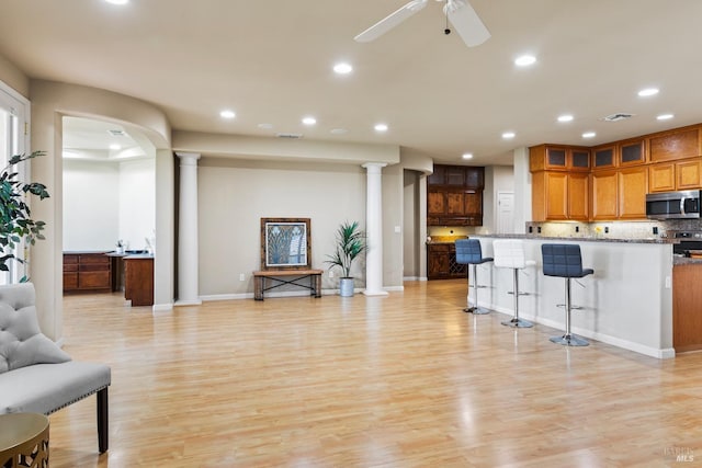 kitchen with light stone countertops, light hardwood / wood-style flooring, decorative columns, and appliances with stainless steel finishes