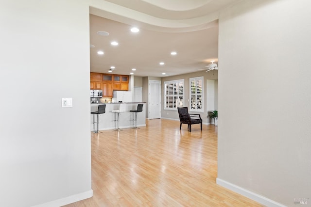 living room featuring light wood-type flooring, ceiling fan, baseboards, and recessed lighting