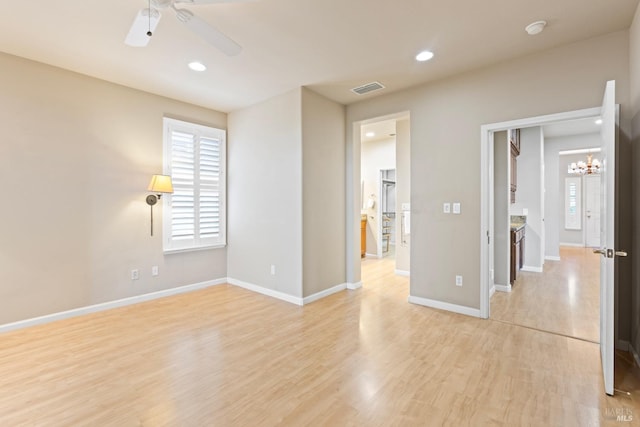 empty room featuring recessed lighting, visible vents, light wood-style flooring, baseboards, and ceiling fan with notable chandelier