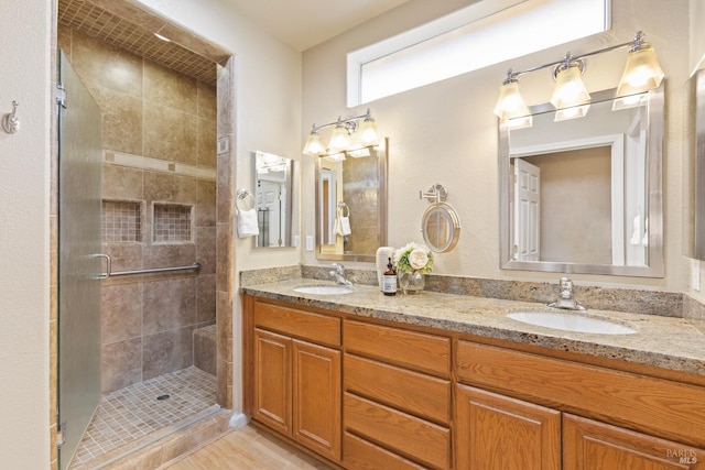 bathroom with a sink, a shower stall, and double vanity