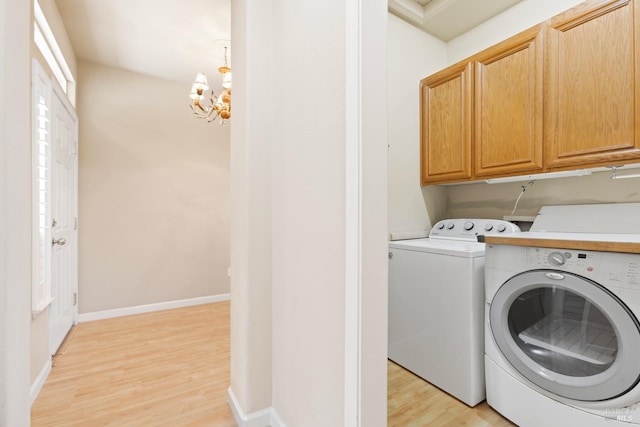 washroom featuring independent washer and dryer, light hardwood / wood-style floors, cabinets, and a chandelier