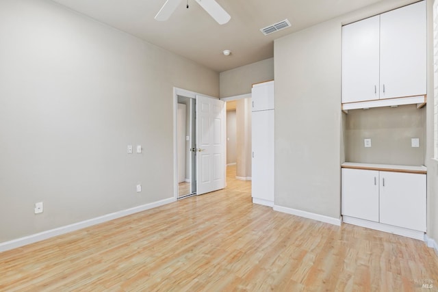 spare room featuring light wood-type flooring, visible vents, ceiling fan, and baseboards