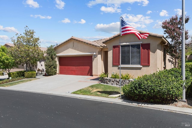 view of front of home featuring an attached garage, a tile roof, concrete driveway, and stucco siding