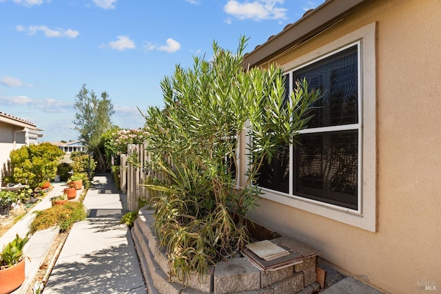 view of side of home with fence and stucco siding