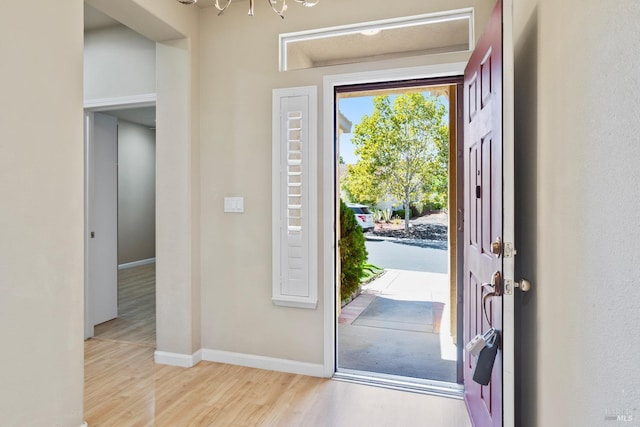 entryway with a notable chandelier, wood finished floors, and baseboards