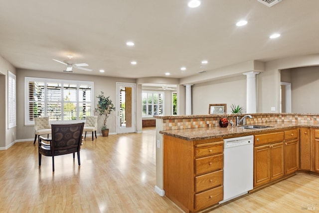 kitchen featuring sink, ornate columns, light stone counters, light hardwood / wood-style flooring, and white dishwasher