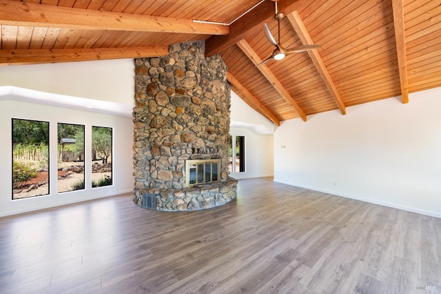 unfurnished living room with a stone fireplace, hardwood / wood-style floors, wooden ceiling, and beam ceiling