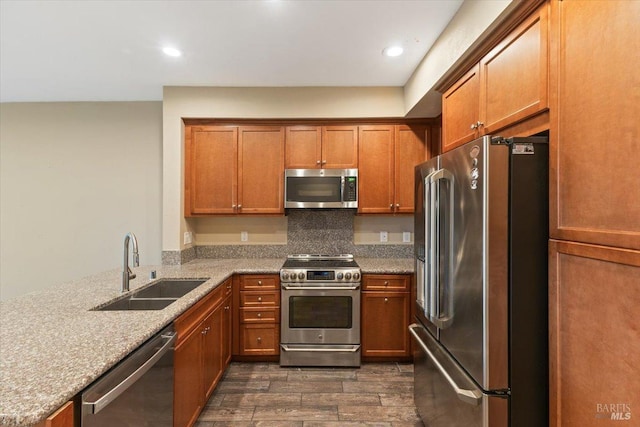 kitchen featuring brown cabinetry, dark wood finished floors, stainless steel appliances, and a sink