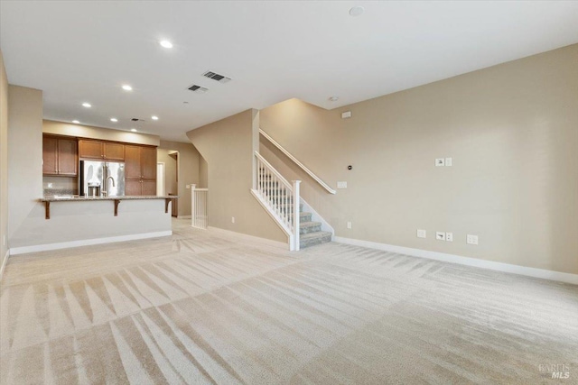 unfurnished living room with light carpet, visible vents, recessed lighting, and stairs