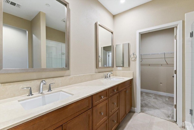 bathroom featuring a spacious closet, visible vents, tile patterned floors, and a sink