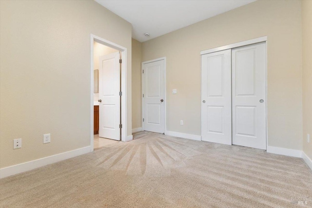 unfurnished bedroom featuring light colored carpet, baseboards, and a closet