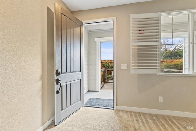 foyer featuring carpet flooring and baseboards