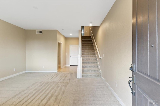 foyer featuring light carpet, stairs, visible vents, and baseboards