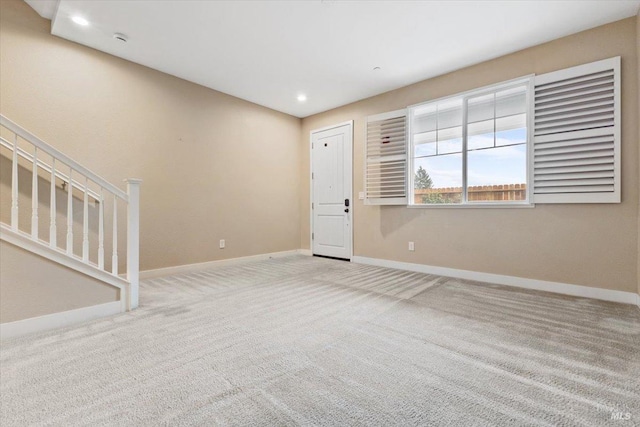 unfurnished living room featuring baseboards, carpet floors, recessed lighting, and stairway