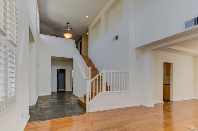 entryway featuring a towering ceiling and wood-type flooring