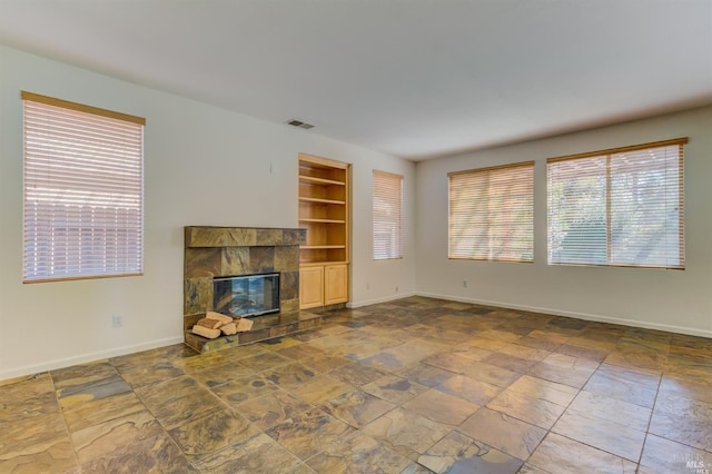 unfurnished living room featuring built in shelves and a fireplace