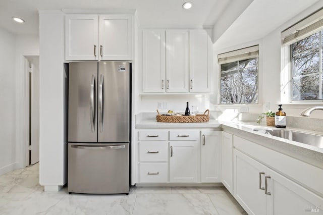 kitchen with white cabinets, sink, and stainless steel fridge