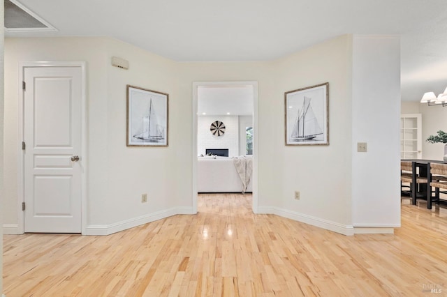 interior space with a chandelier, light hardwood / wood-style floors, and a brick fireplace