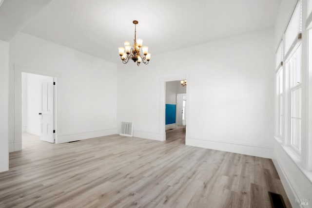 empty room featuring light wood-type flooring, baseboards, visible vents, and a notable chandelier