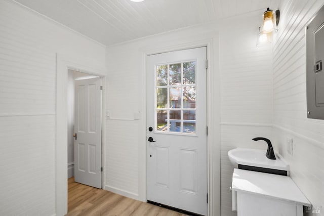 entryway with light wood-style floors and crown molding