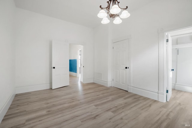 interior space featuring baseboards, light wood finished floors, and an inviting chandelier