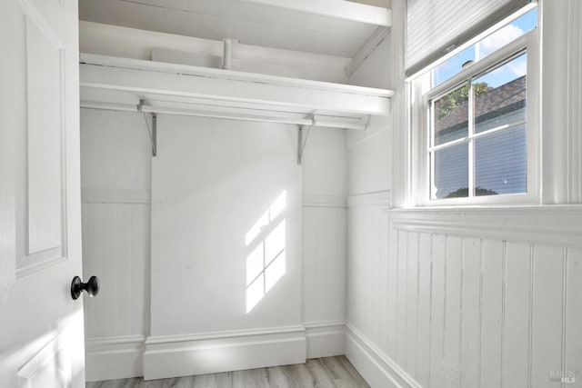 interior space with light wood-style floors and a wainscoted wall