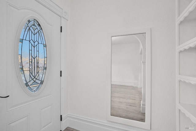 foyer with arched walkways and wood finished floors