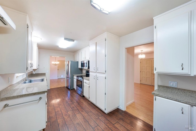 kitchen featuring white cabinetry, a notable chandelier, light stone counters, and stainless steel appliances