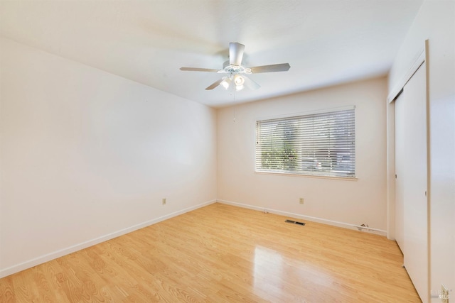 unfurnished bedroom featuring ceiling fan, a closet, and light wood-type flooring