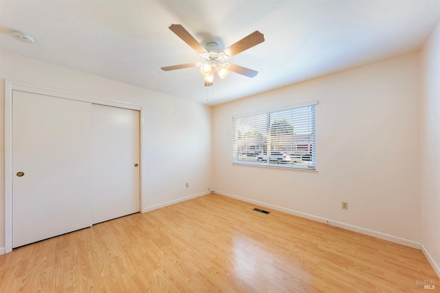 unfurnished bedroom featuring light wood-type flooring, ceiling fan, and a closet