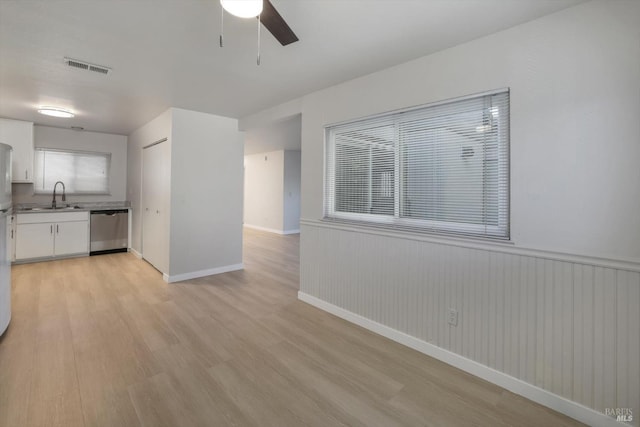 kitchen with sink, dishwasher, ceiling fan, white cabinetry, and light hardwood / wood-style floors