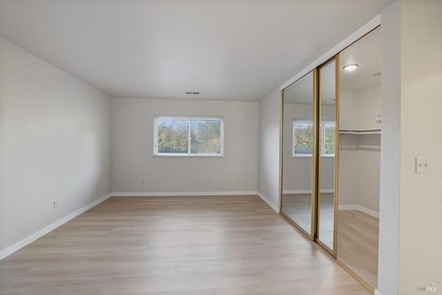 unfurnished bedroom with a closet and light wood-type flooring