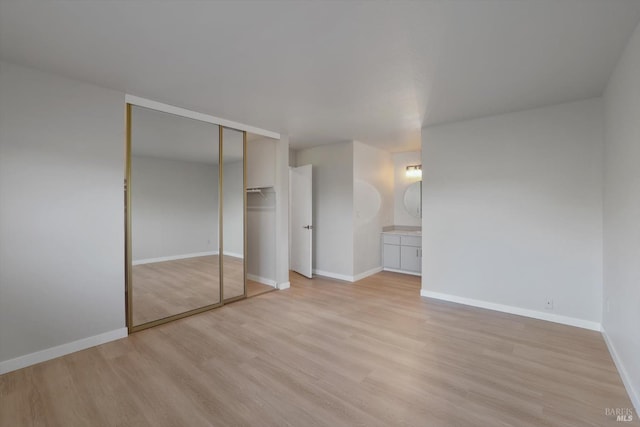 unfurnished bedroom with connected bathroom and light hardwood / wood-style flooring