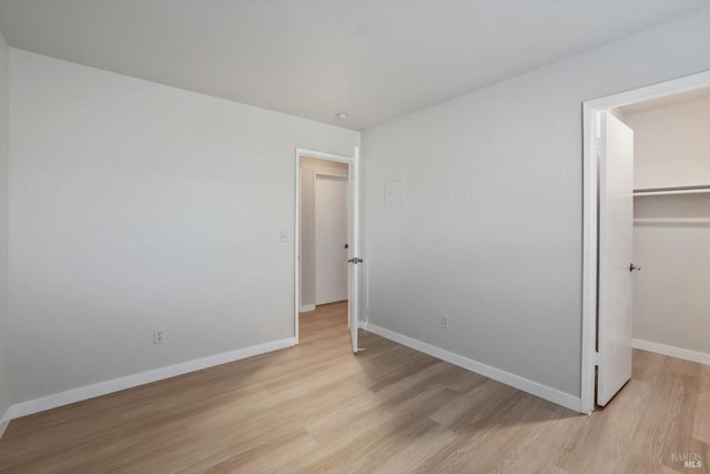 bedroom featuring a walk in closet, light hardwood / wood-style flooring, and a closet