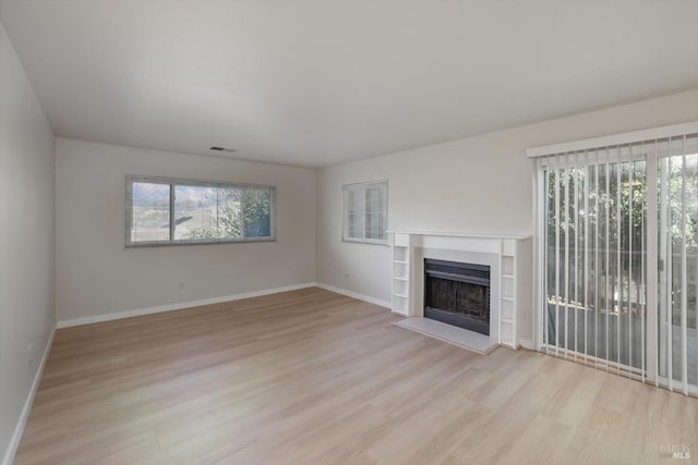 unfurnished living room featuring a wealth of natural light and light hardwood / wood-style flooring