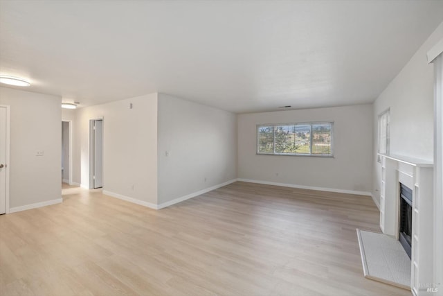 unfurnished living room with a fireplace and light wood-type flooring