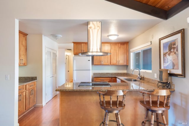 kitchen with sink, stovetop, white refrigerator, island exhaust hood, and kitchen peninsula