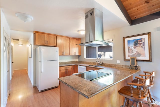 kitchen featuring white appliances, island range hood, kitchen peninsula, and a breakfast bar