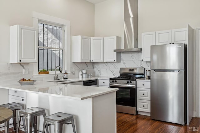 kitchen featuring a kitchen bar, sink, white cabinetry, appliances with stainless steel finishes, and kitchen peninsula