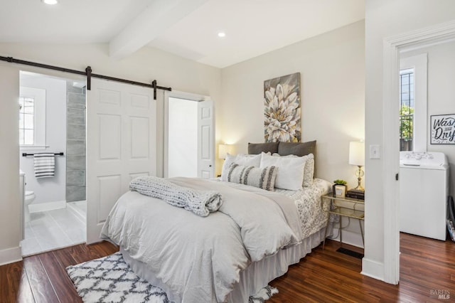 bedroom with washer / dryer, vaulted ceiling with beams, a barn door, dark wood-type flooring, and ensuite bath