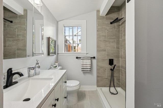 bathroom featuring tile patterned floors, toilet, vaulted ceiling, a tile shower, and vanity