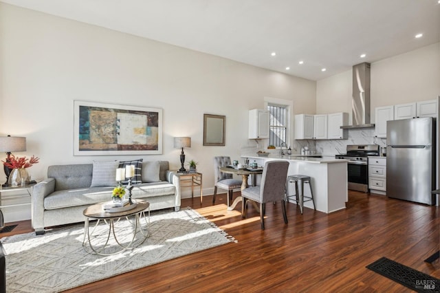 living room featuring a towering ceiling, dark hardwood / wood-style flooring, and sink