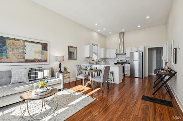 living room featuring dark hardwood / wood-style floors, sink, and a towering ceiling