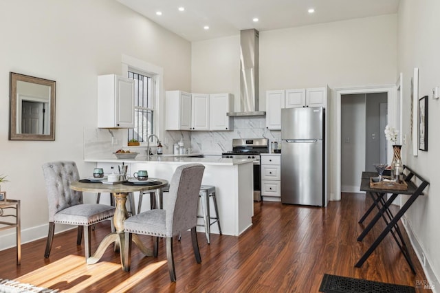 kitchen featuring appliances with stainless steel finishes, a towering ceiling, and white cabinets