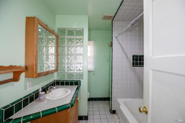 full bathroom featuring tile patterned flooring, vanity, tiled shower / bath combo, and toilet