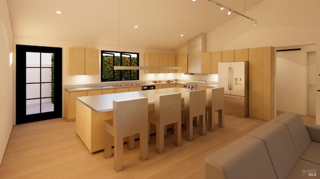 kitchen featuring light brown cabinetry, a sink, a kitchen island, freestanding refrigerator, and light countertops